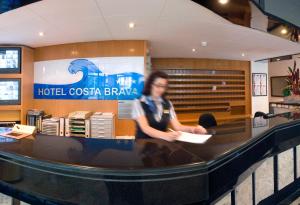 un hombre sentado en un mostrador en una farmacia de casino de hotel en GHT Costa Brava & Spa, en Tossa de Mar