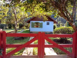 ein roter Zaun vor einem kleinen Haus in der Unterkunft Pousada Sítio das Astrapéias in Visconde De Maua