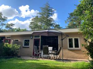 a house with a table and chairs and an umbrella at Bonte Specht: tot rust komen in de natuur! in Otterlo