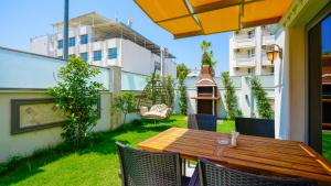 een patio met een houten tafel en stoelen in een tuin bij Green Beyza Suites in Antalya