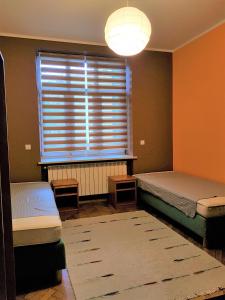 a bedroom with two beds and a window with a lamp at Center Rooms in Jarosław