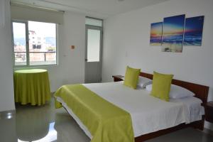 Un dormitorio con una cama con una manta verde. en Hotel Milán, en Duitama