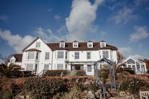 een groot wit huis met een speeltuin ervoor bij The Bay Hotel in Coverack