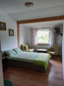 a bedroom with a bed and a chair and a window at Marka Pokoje Gościnne in Mielno