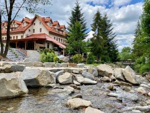 a river with rocks in front of a building at Hotel Fero Lux in Korbielów