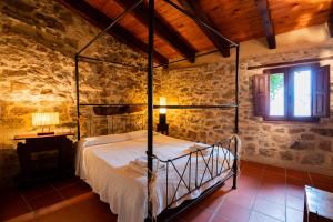 1 dormitorio con cama de metal en una pared de piedra en El Cau dels Somnis, en La Cuevarruz