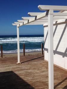 a white pergola on a beach with the ocean at Traumblick in Valledoria