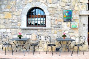 vier Tische und Stühle vor einer Steinmauer in der Unterkunft Agriturismo dell'Altopiano in Serle