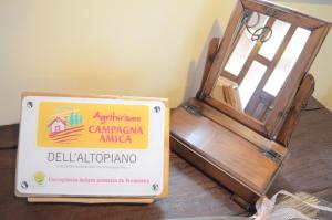 Serle的住宿－Agriturismo dell'Altopiano，坐在一张桌子上的标志,就在一扇敞开的门旁边
