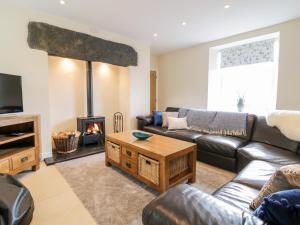 a living room with a leather couch and a fireplace at Bryn Mawndy in Corwen