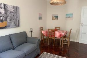 een woonkamer met een bank en een eettafel bij Casa do Largo Sardinha - Very central apartment in Lissabon