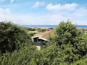 Skåstrupにある8 person holiday home in Bogenseの背景の木々と海を背景にした家