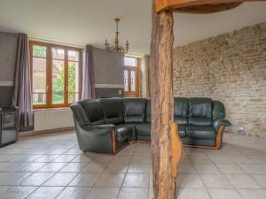 sala de estar con sofá de cuero negro y ventanas en Vintage holiday home with private garden, en Nouart