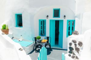 niebieskie drzwi na białym domu ze stołem i krzesłami w obiekcie Blessed Blue Boutique Cave Suite w mieście Oia