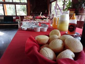 a table with a red table cloth with bread on it at Pousada Sítio das Astrapéias in Visconde De Maua