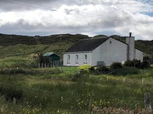 een wit huis in het midden van een veld bij 39 Gravir, Isle of Lewis in Graver