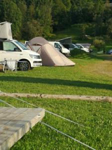 eine Gruppe von Zelten und Autos, die auf einem Feld geparkt sind in der Unterkunft Camping Garden Park in Radovljica