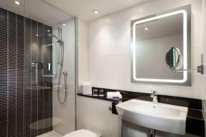a bathroom with a sink and a shower and a mirror at Radisson Hotel and Conference Centre London Heathrow in Hillingdon