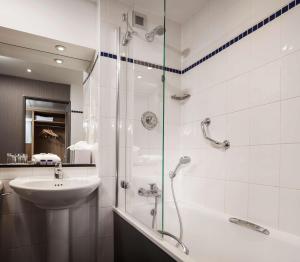 a bathroom with a shower, sink, and mirror at Radisson Hotel and Conference Centre London Heathrow in Hillingdon