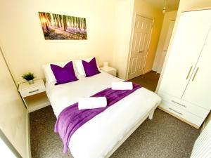 ein Schlafzimmer mit einem großen Bett mit lila Kissen in der Unterkunft City Centre Apartment - Free Parking, Fast Wifi, Smart TV with Netflix and Xbox by Yoko Property in Milton Keynes