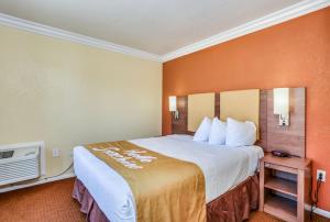 a hotel room with a large bed with orange walls at Days Inn by Wyndham Palm Springs in Palm Springs