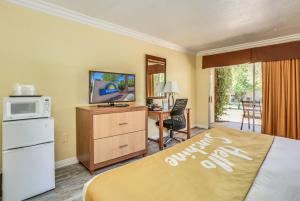 a hotel room with a bed and a microwave and a desk at Days Inn by Wyndham Palm Springs in Palm Springs