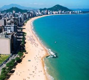 a beach with a group of people in the water at Zaca’s House in Vila Velha
