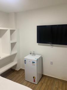 a small refrigerator in a room with a tv on the wall at Zaca’s House in Vila Velha