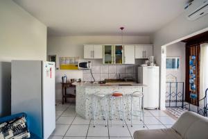 eine Küche mit weißen Geräten und einer Theke mit Hockern in der Unterkunft Loft com vista ao mar in São Sebastião