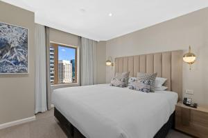 a hotel room with a large bed and a large window at The Sebel Quay West Suites Sydney in Sydney