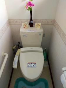 a bathroom with a toilet with a vase with flowers on it at Echizen Guesthouse TAMADA in Fukui