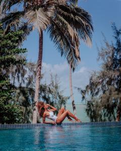 dos mujeres tumbadas al lado de una piscina con palmeras en Vila de Taipa Exclusive Hotel, en Japaratinga