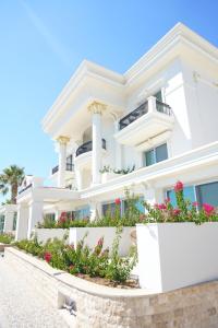 a white house with flowers in front of it at Kıvrakzade Otel in Ayvalık