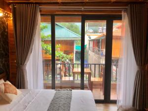 Mai Chau Green Ecohouse في Hòa Bình: غرفة نوم بسرير ونافذة كبيرة