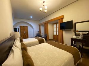 a hotel room with two beds and a television at Hotel Casa Faroles Centro Hist&oacute;rico in Zacatecas