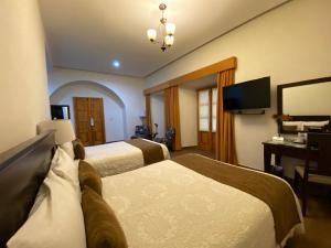 Cette chambre comprend deux lits et une télévision. dans l'établissement Hotel Casa Faroles Centro Histórico, à Zacatecas