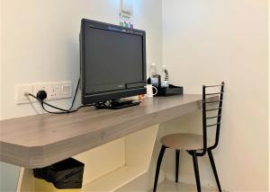 a computer monitor sitting on a desk with a chair at Green Hotel in Puchong