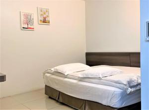 Bett mit weißer Bettwäsche und Kissen in einem Zimmer in der Unterkunft Green Hotel in Puchong