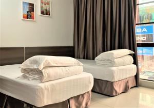2 łóżka pojedyncze w pokoju z oknem w obiekcie Green Hotel w mieście Puchong