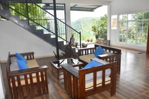 a living room with chairs and tables and a staircase at Hotel H2O in Gampola