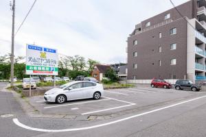un coche blanco aparcado en un aparcamiento al lado de un edificio en Inuyama Miyako Hotel, en Inuyama