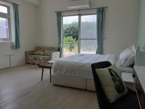a bedroom with a bed and a couch and a window at Green Grass B&B in Hualien City