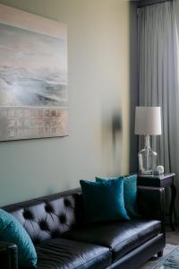 a living room with a leather couch and a lamp at The Old Confectionery in Oamaru