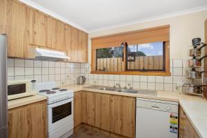 a kitchen with wooden cabinets and a white stove top oven at Jenny Wrens Nest @ Cowes in Cowes