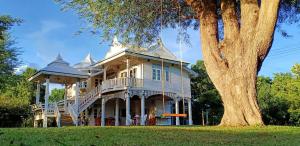 a large white house with a porch and a tree at Rai Lung Tui Homestay in Prachuap Khiri Khan