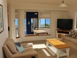 a living room with a couch and a tv at Ocean Views air conditioned luxury with beautiful ocean views in Anna Bay