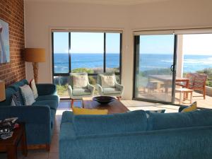 a living room with blue couches and a view of the ocean at Ocean Views air conditioned luxury with beautiful ocean views in Anna Bay