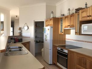 a kitchen with wooden cabinets and a white refrigerator at Ocean Views air conditioned luxury with beautiful ocean views in Anna Bay