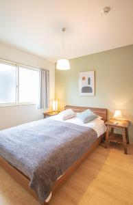 um quarto com uma cama grande e duas mesas em Ecru Haruyoshi Logement em Fukuoka