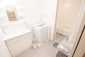a white bathroom with a sink and a refrigerator at Ecru Haruyoshi Logement in Fukuoka